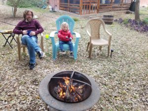 photo of eric and kiddo sitting around a campfire in the backyard.